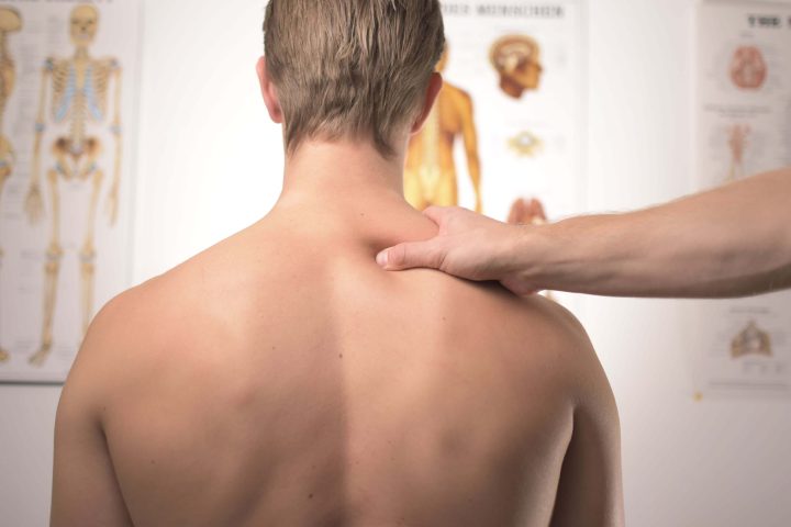 A clinician assessing a patient's neck and upper back