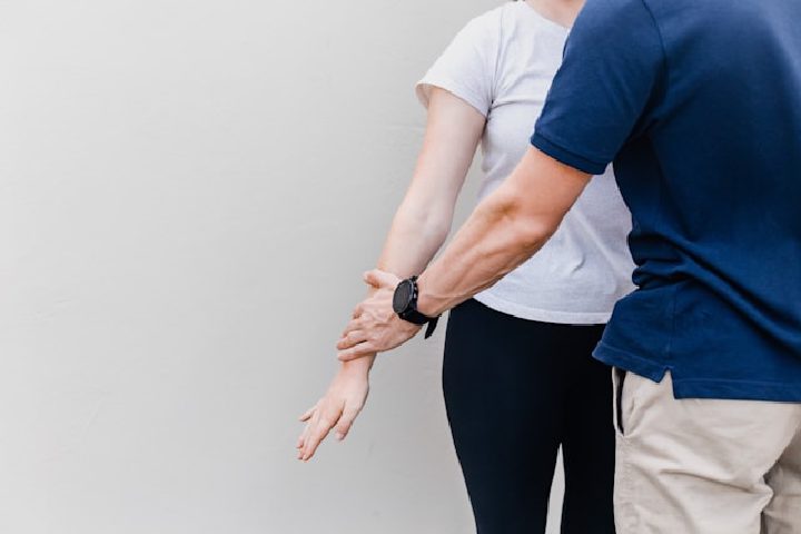 A clinician assessing a patient's wrist after a workplace or motor vehicle injury